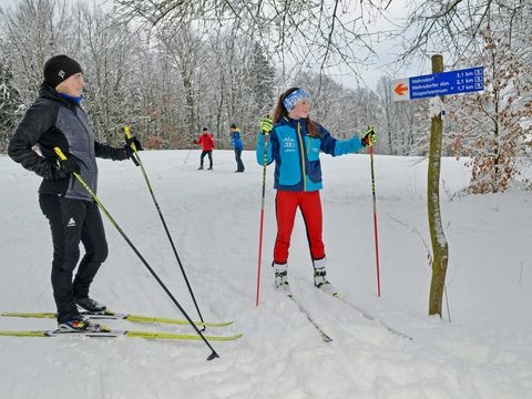 Langläufer stehen am Wegweisre im verschneiten Winterwald