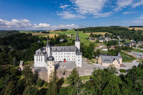 Das Schloss Purschenstein steht auf einem kleinen Hügel umgeben von Wald, Wiesen und einzelnen Häusern.