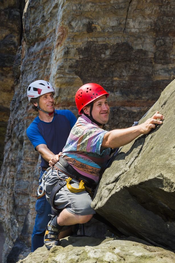 Ein junger Mann mit Down Syndrom klettert auf einem Felsen in der Sächsischen Schweiz 