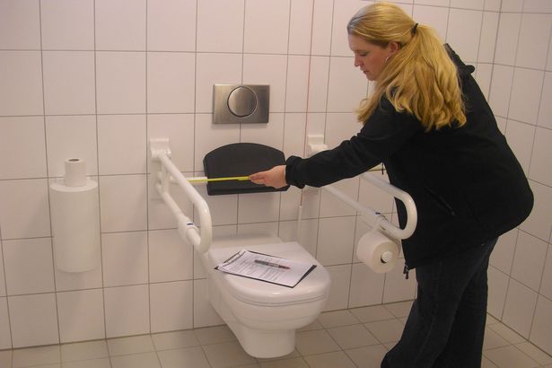 Eine Frau prüft die Barrierefreiheit einer Behindertentoilette.