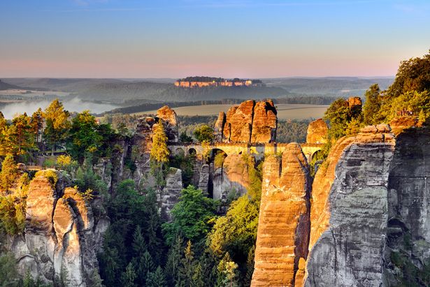 Die Sandsteinfelsen der Sächsischen Schweiz leuchten im Abendlicht, dazwischen die berühmte Basteibrücke.