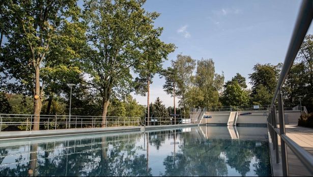 Ein Schwimmbecken des Bilzbades von Radebeul. Rundherum stehen Bäume. 